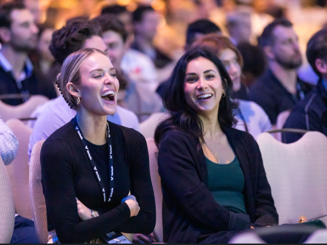 Senior Regional Sales Manager, Olivia Sanderson, laughs alongside a colleague while listening to a speaker during VerkadaOne.